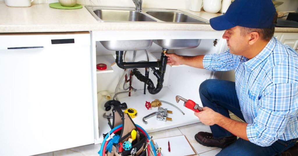 A 24-hour emergency plumber fixing a clogged drain in the kitchen